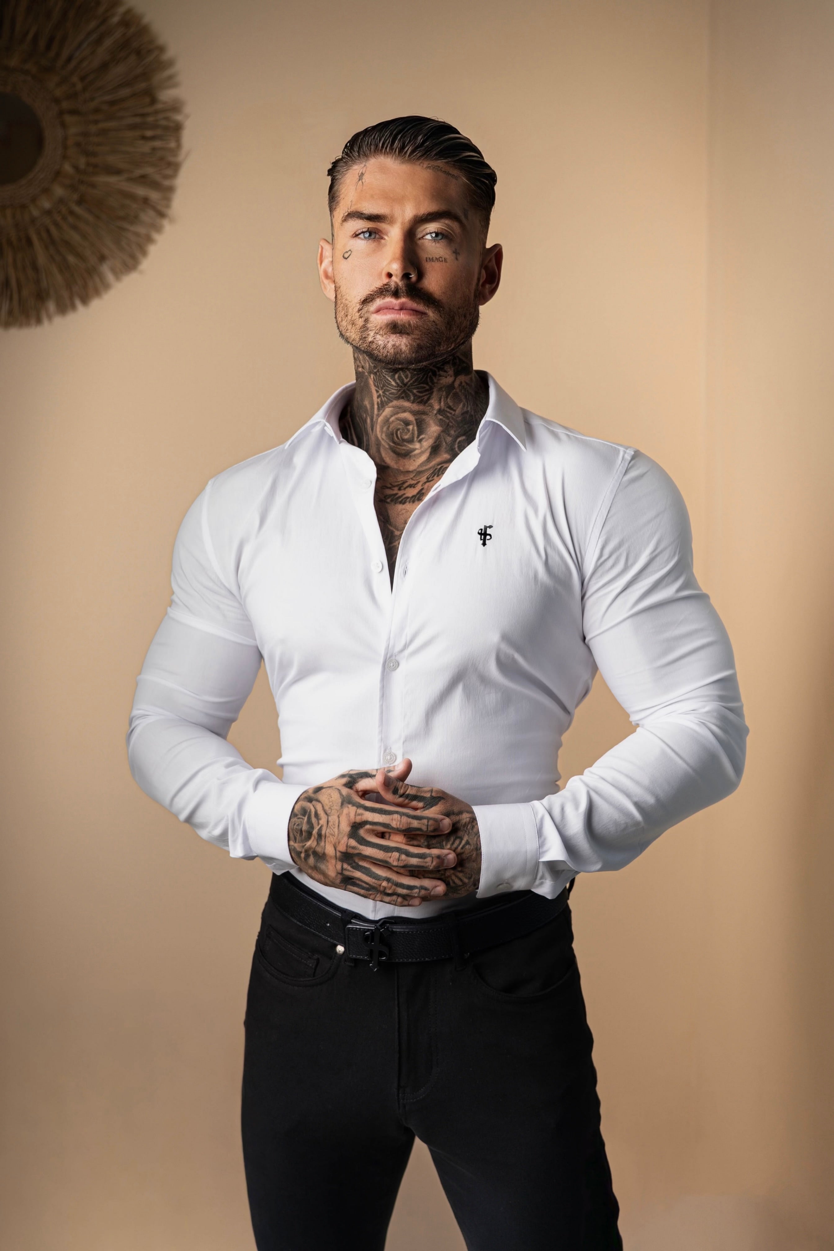 Man wearing a white dress shirt and black pants against a beige background