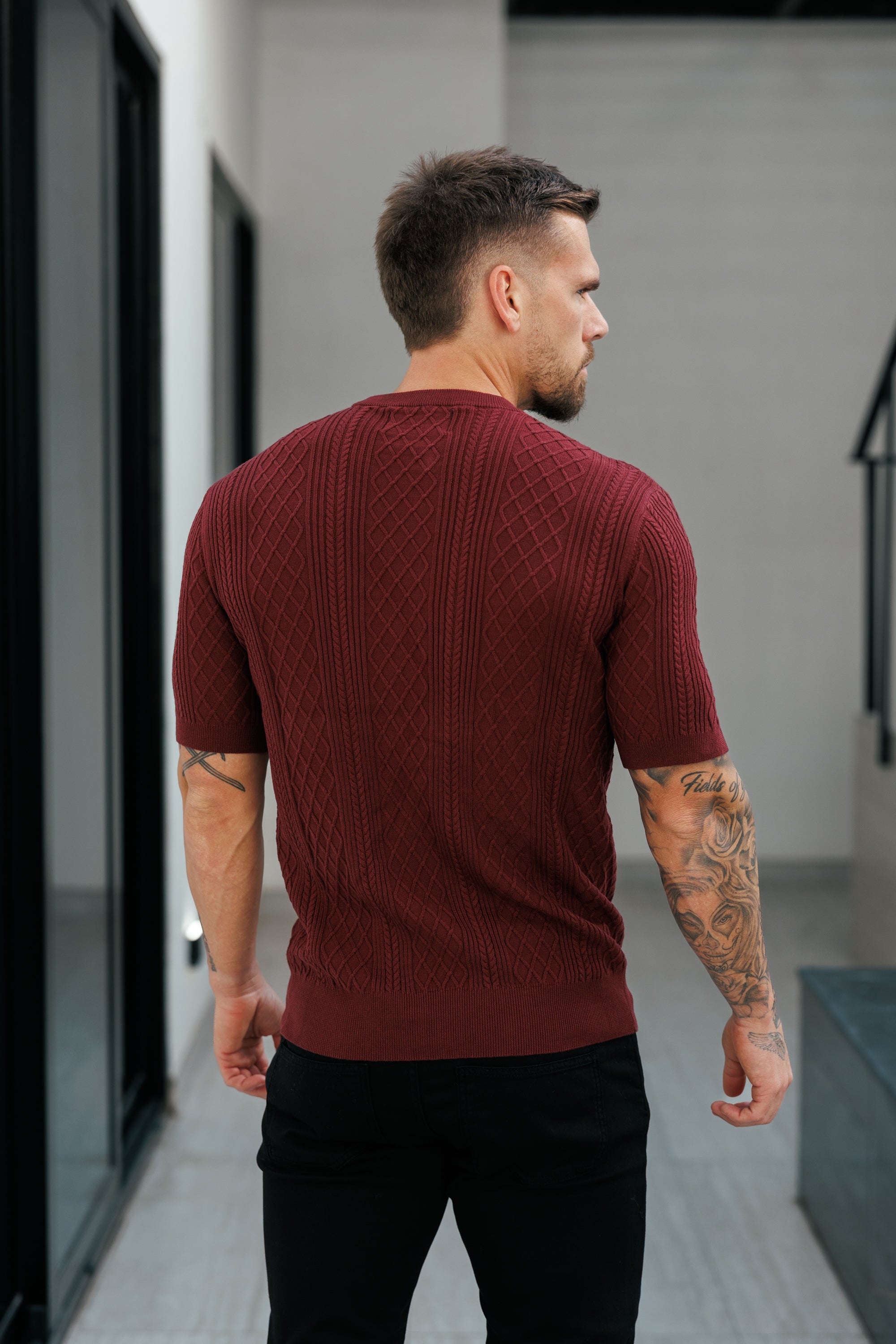 Man wearing a maroon sweater walking in an indoor setting